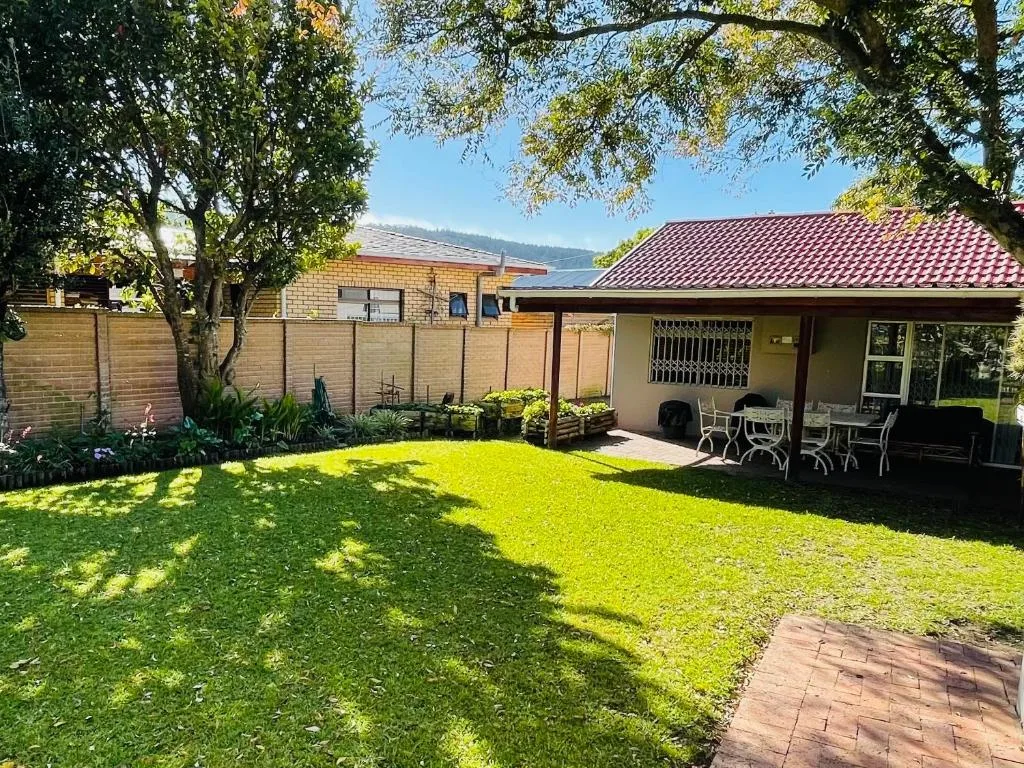 Brick home with covered patio, manicured lawn, and mountain views