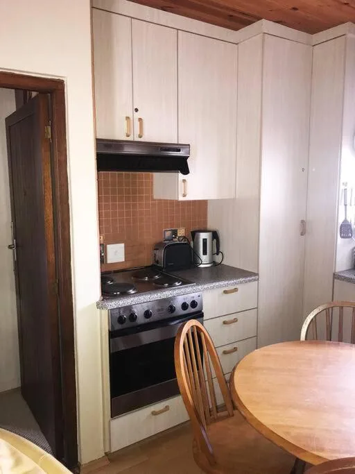 Compact kitchen with white cabinetry, gas stove, and terracotta tile backsplash