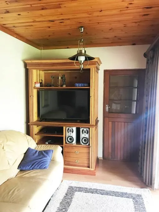 Cozy lounge with wooden TV cabinet, cream sofa, and wooden ceiling