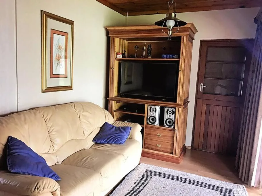 Living room with cream sofa, wooden TV entertainment unit, and blue cushions