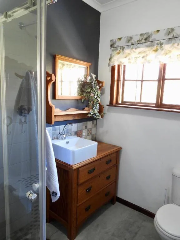 Bathroom with wooden vanity, white basin sink, and shower enclosure