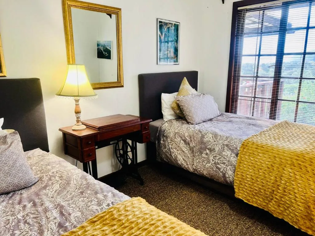 Bright bedroom with twin beds, bedside table, lamp, and window views