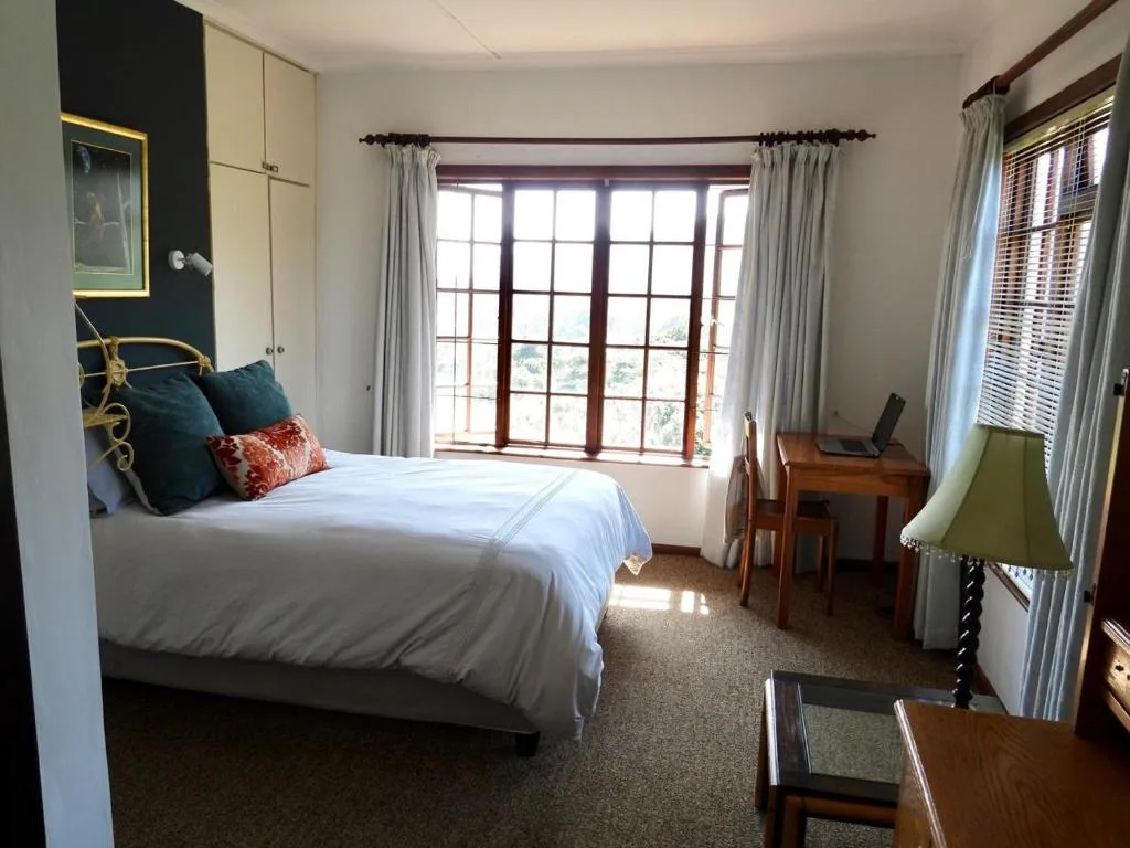 Bright bedroom with queen bed, large windows, and garden views