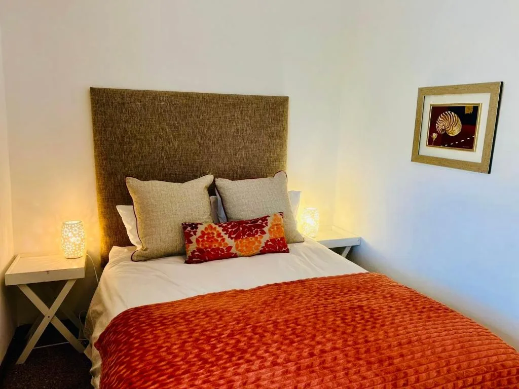 Cozy bedroom with upholstered headboard, warm lighting, decorative pillows