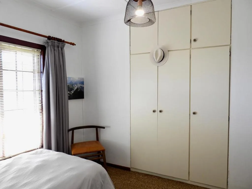 Bright bedroom with white wardrobe, window, and minimalist decor