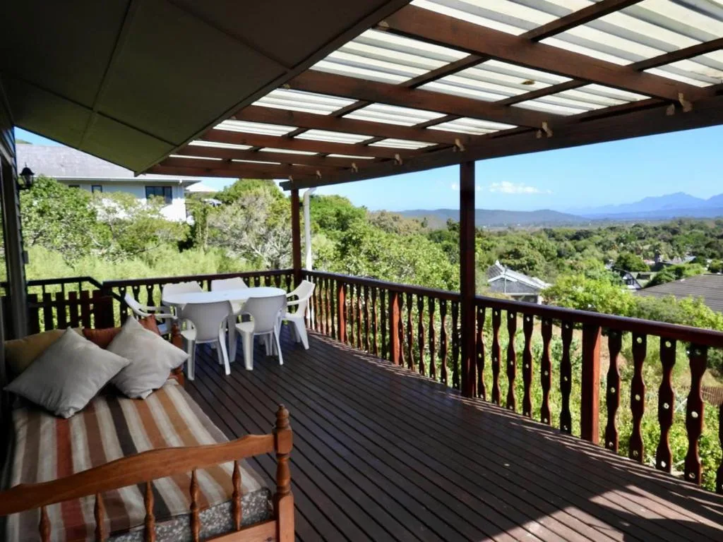 Covered deck with lounge seating and dining table overlooking lush garden