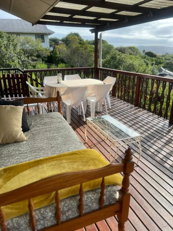 Covered wooden deck with dining table, lounge seating, mountain views