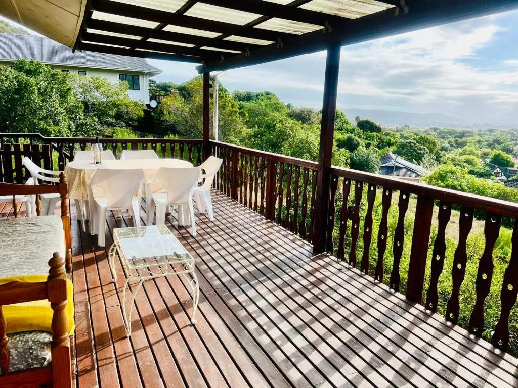 Spacious covered deck with dining table overlooking lush green valleys and distant mountains