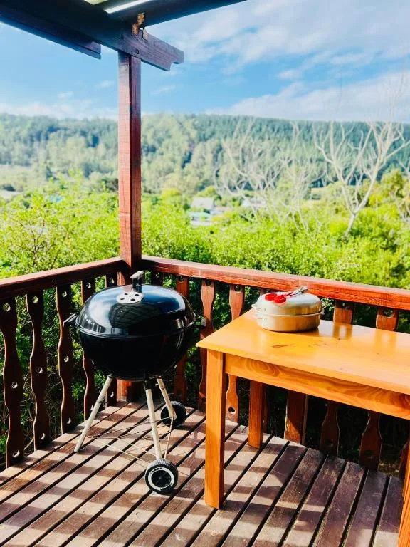 Wooden deck with braai grill, table, and scenic forest views