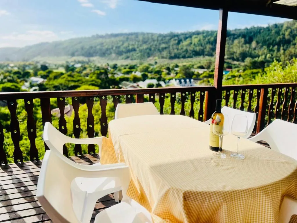 Outdoor dining table on covered deck overlooking lush valley landscape
