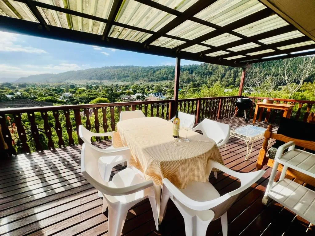 Shaded deck with dining table overlooking lush valley and forested mountains