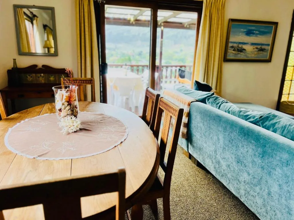 Round dining table with chairs overlooking scenic valley landscape through glass doors