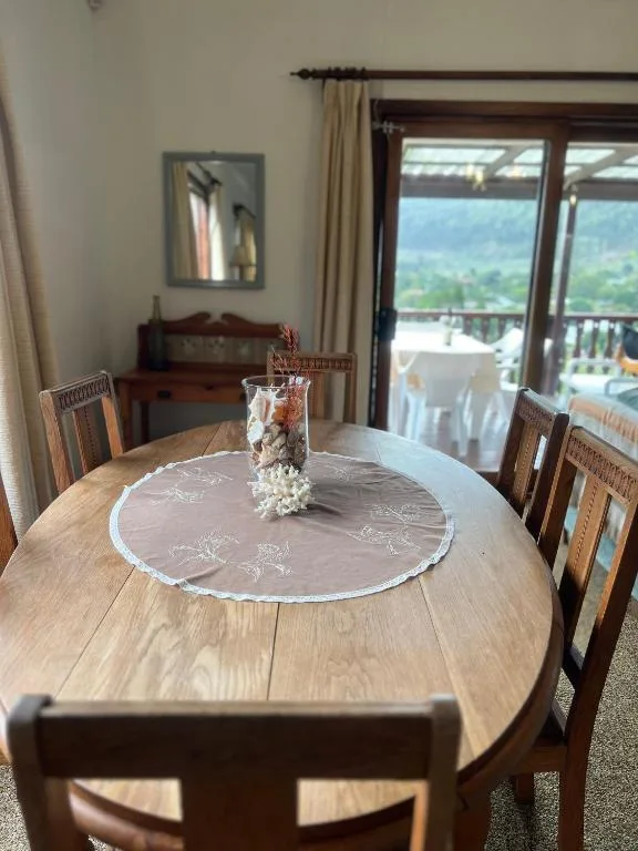 Round wooden dining table with decorative tablecloth and mountain view doors