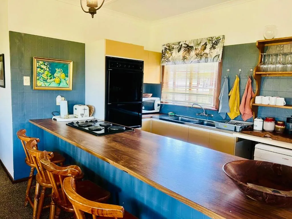 Bright kitchen with wooden counter, black stove, and blue tile backsplash
