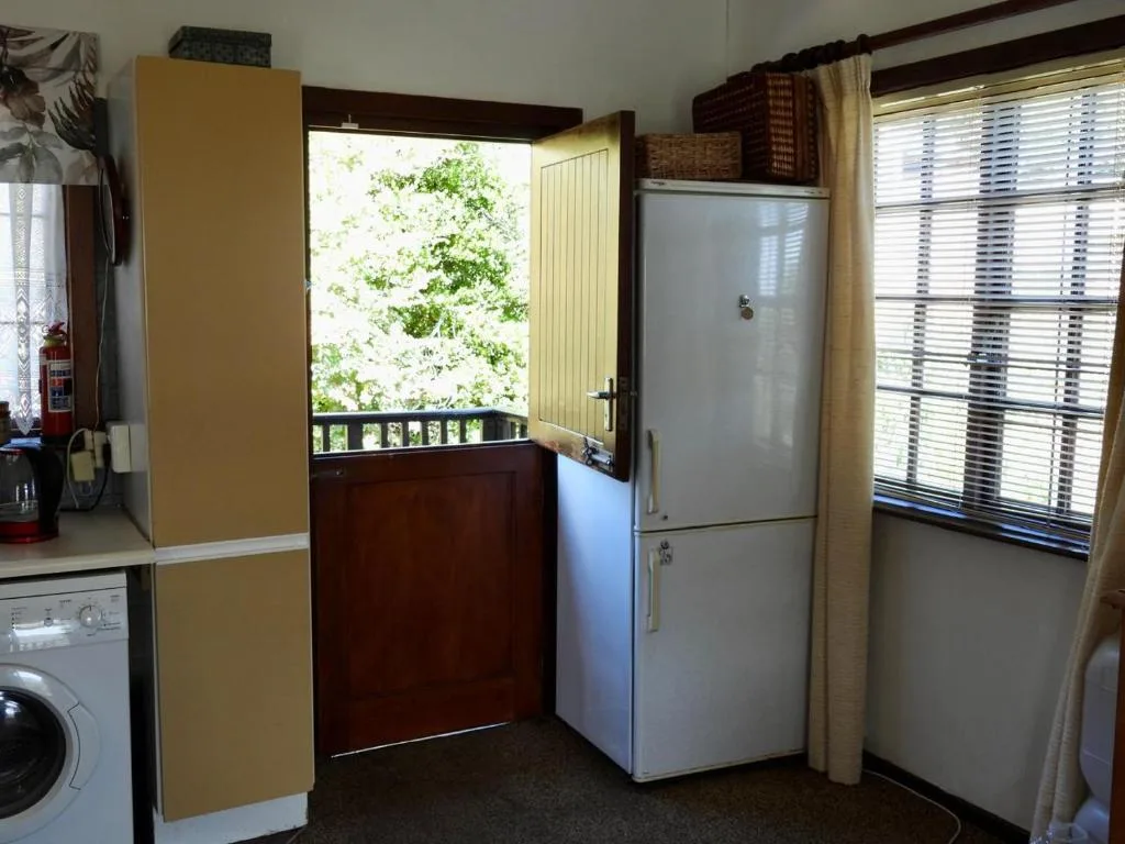 Kitchen with refrigerator, washing machine, and garden view through door
