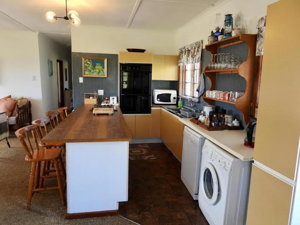 Open-plan kitchen with wooden cabinetry, appliances, and dining counter seating