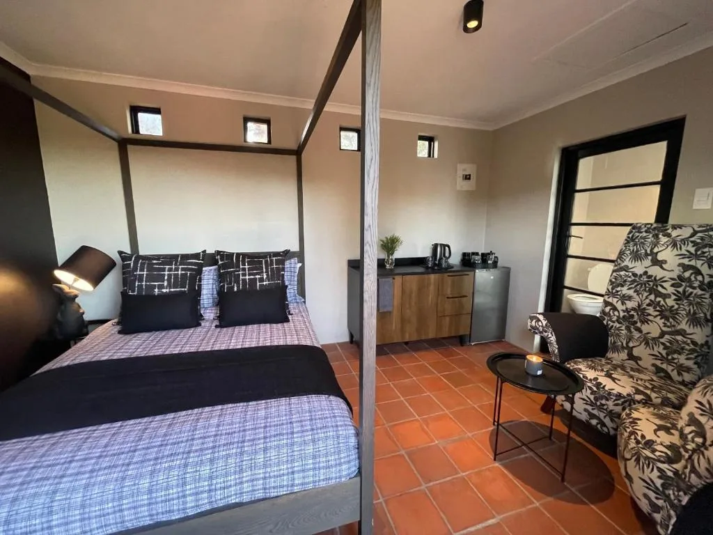 Spacious bedroom with four-poster bed, wooden dresser, and seating area