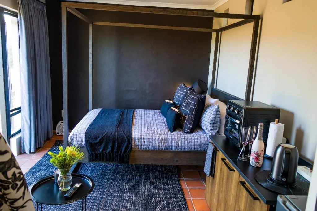 Spacious bedroom with four-poster bed, blue bedding, and modern furnishings