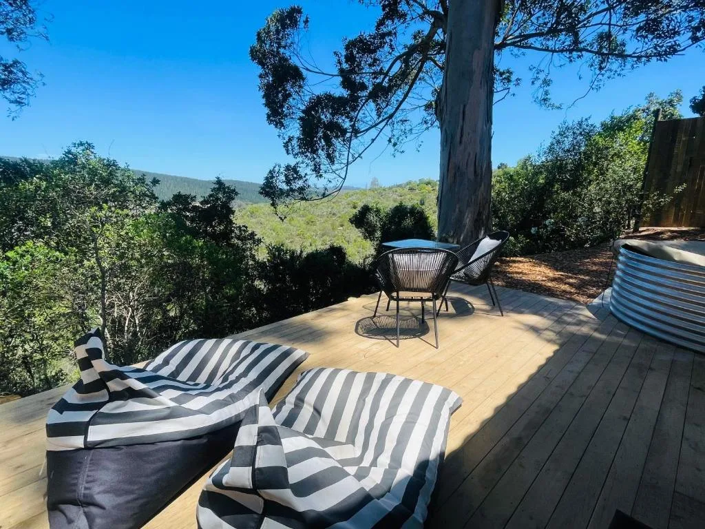 Wooden deck with loungers overlooking forested mountains and valley views