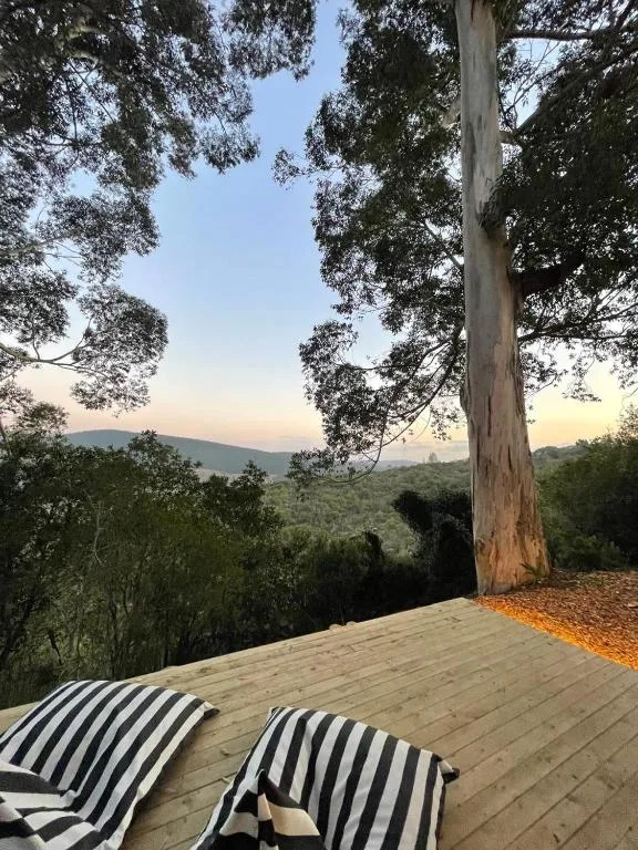 Wooden deck with striped loungers overlooking green mountain valleys