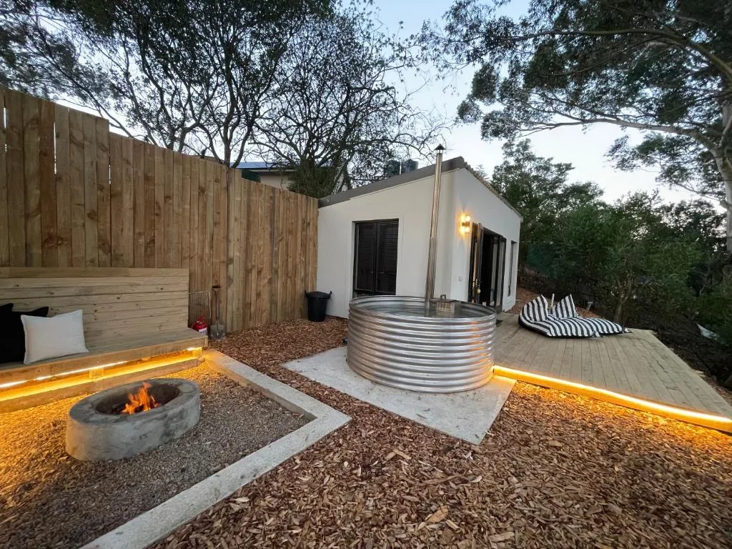 Modern outdoor deck with fire pit, ambient lighting, and accommodation building