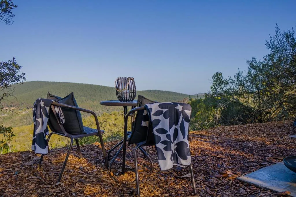Outdoor seating area with chairs overlooking forested mountain landscape