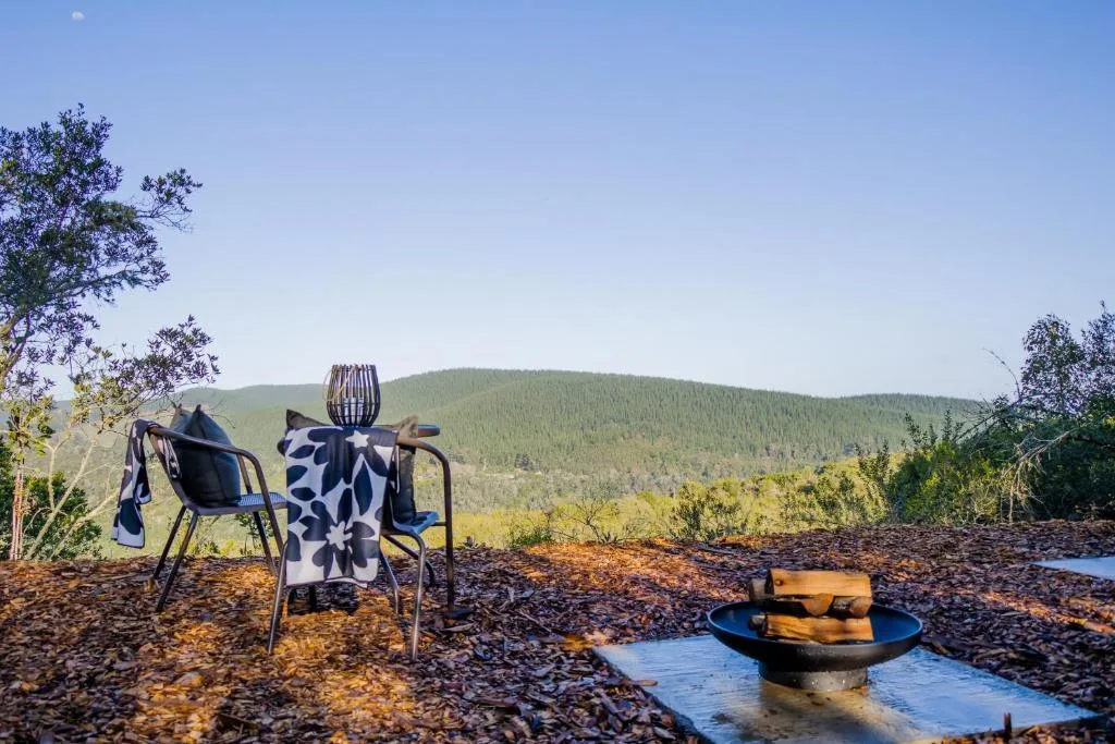 Outdoor seating area with chairs overlooking forested mountains and valley