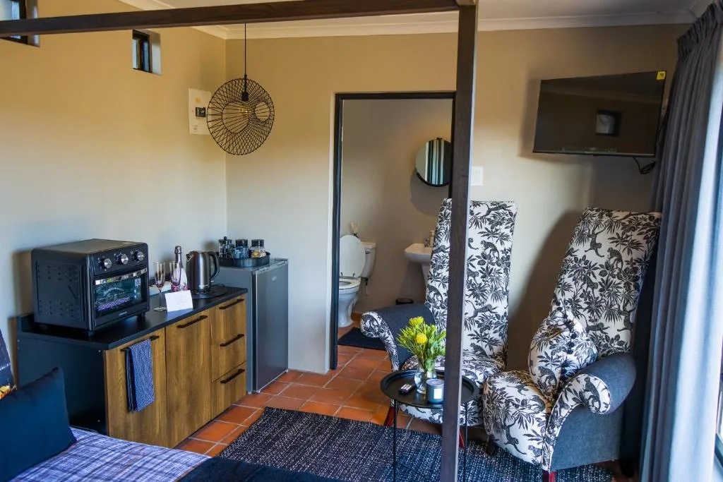 Modern studio apartment showing kitchenette, seating area, and bedroom entrance