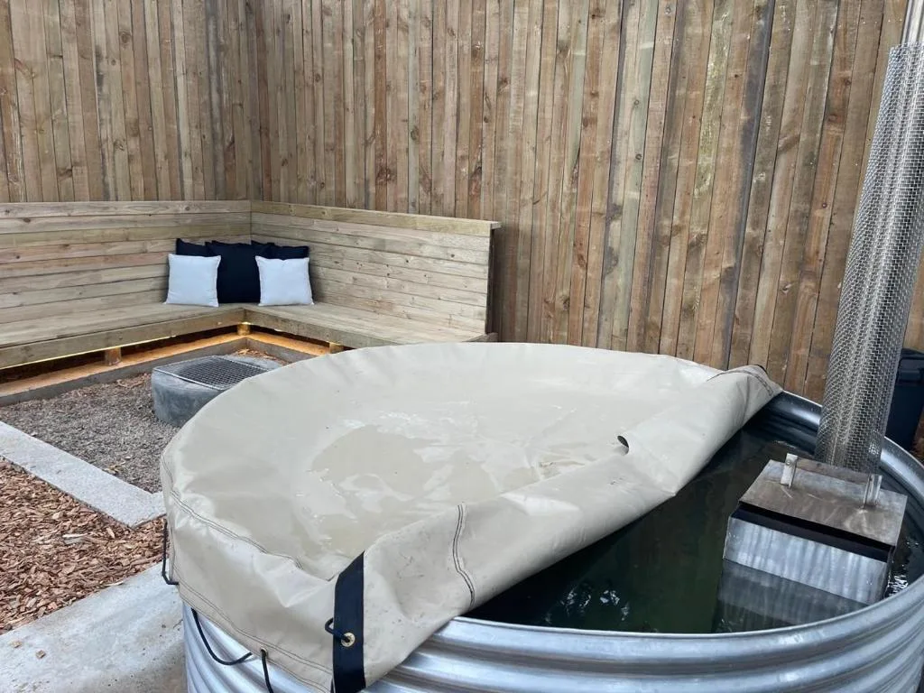 Covered hot tub with wooden bench seating area in background
