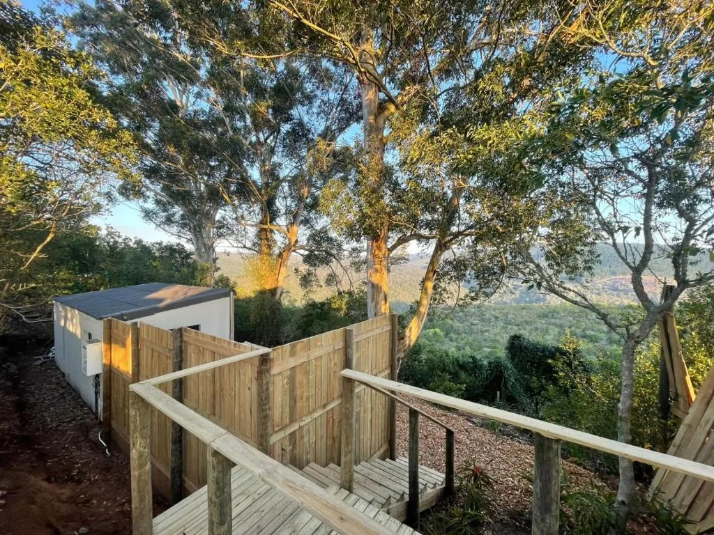 Wooden deck overlooking lush green valley and distant forested mountains