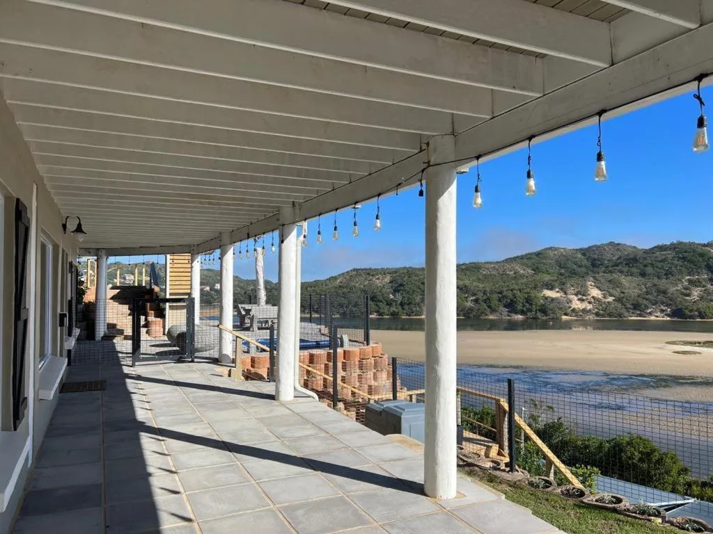 Covered patio with pendant lights overlooking lagoon and green hills