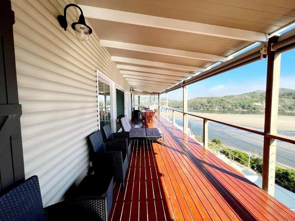 Covered wooden deck with seating overlooking lagoon and mountains