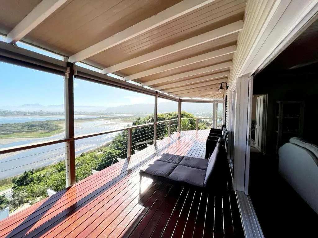 Covered wooden deck with lounge seating overlooking lagoon and mountains