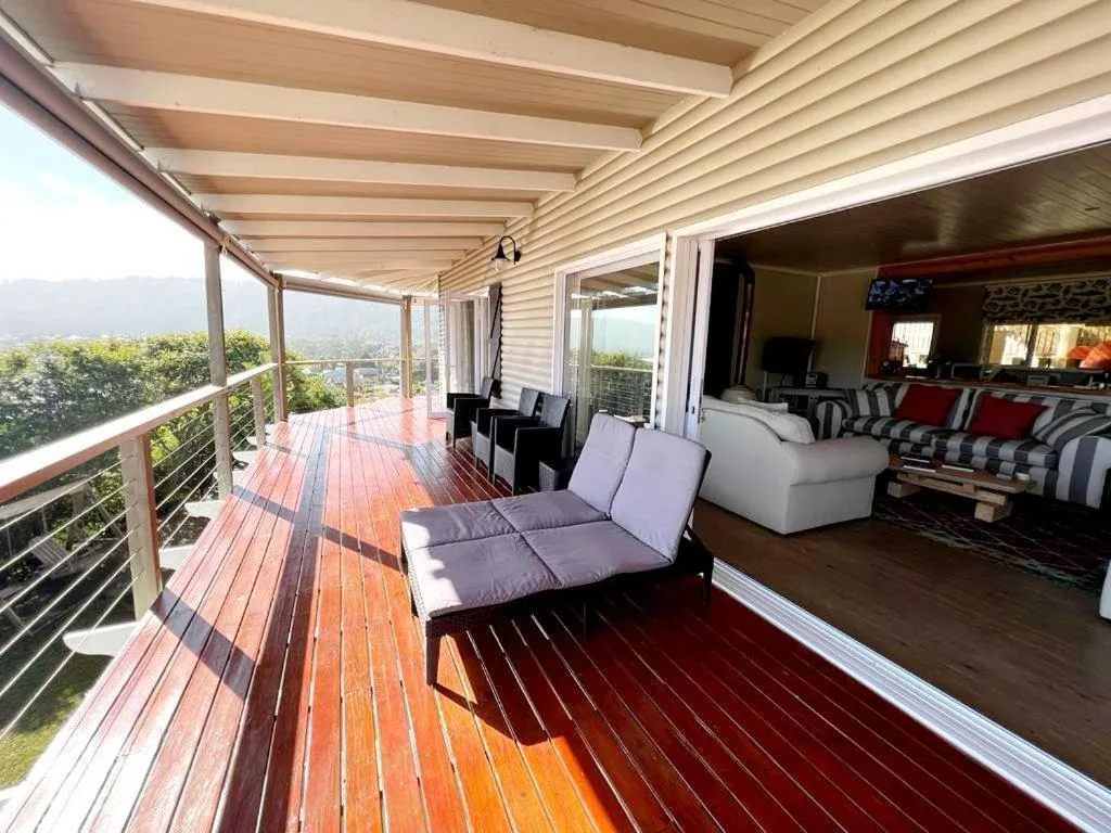 Wooden deck with lounge chairs overlooking lush green hills and valleys