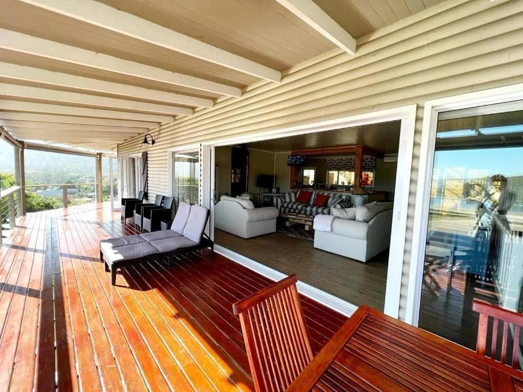 Spacious wooden deck with covered pergola overlooking lagoon and lounge beyond
