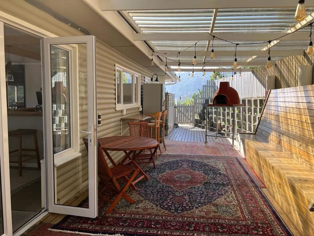 Covered outdoor deck with dining table, chairs, and mountain views