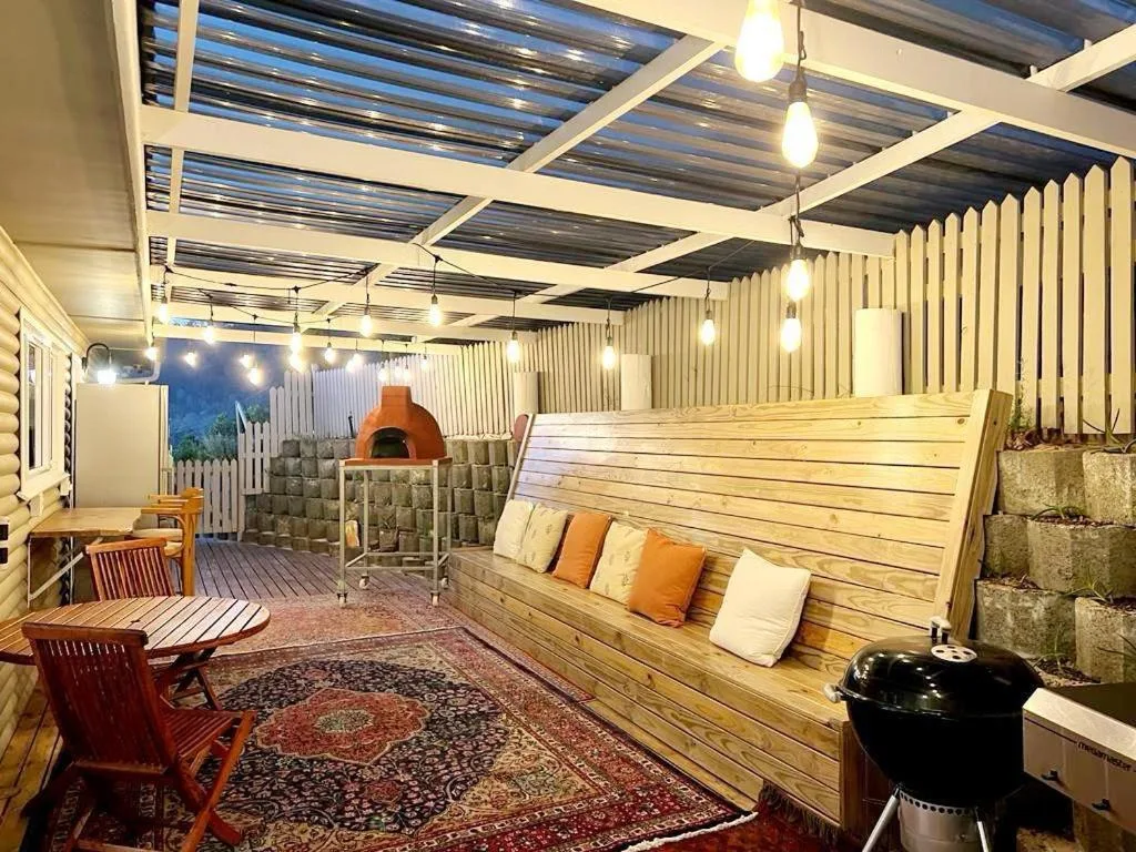 Covered outdoor entertaining area with braai, seating, and ambient lighting