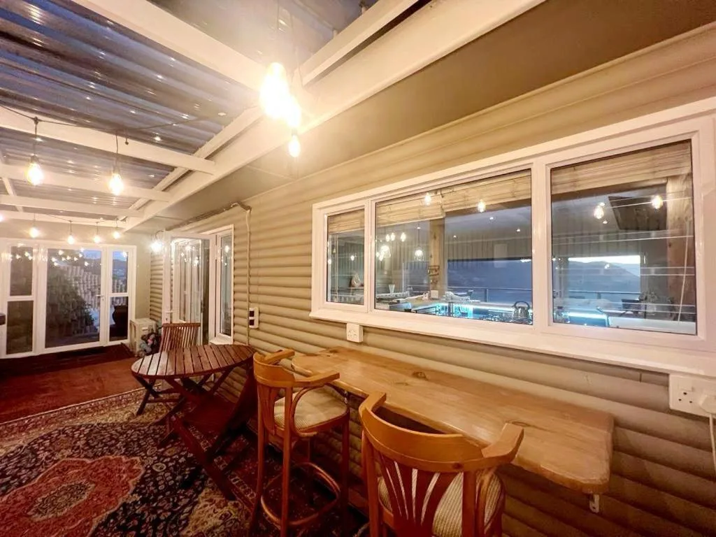 Covered outdoor deck with wooden chairs and ocean views at dusk