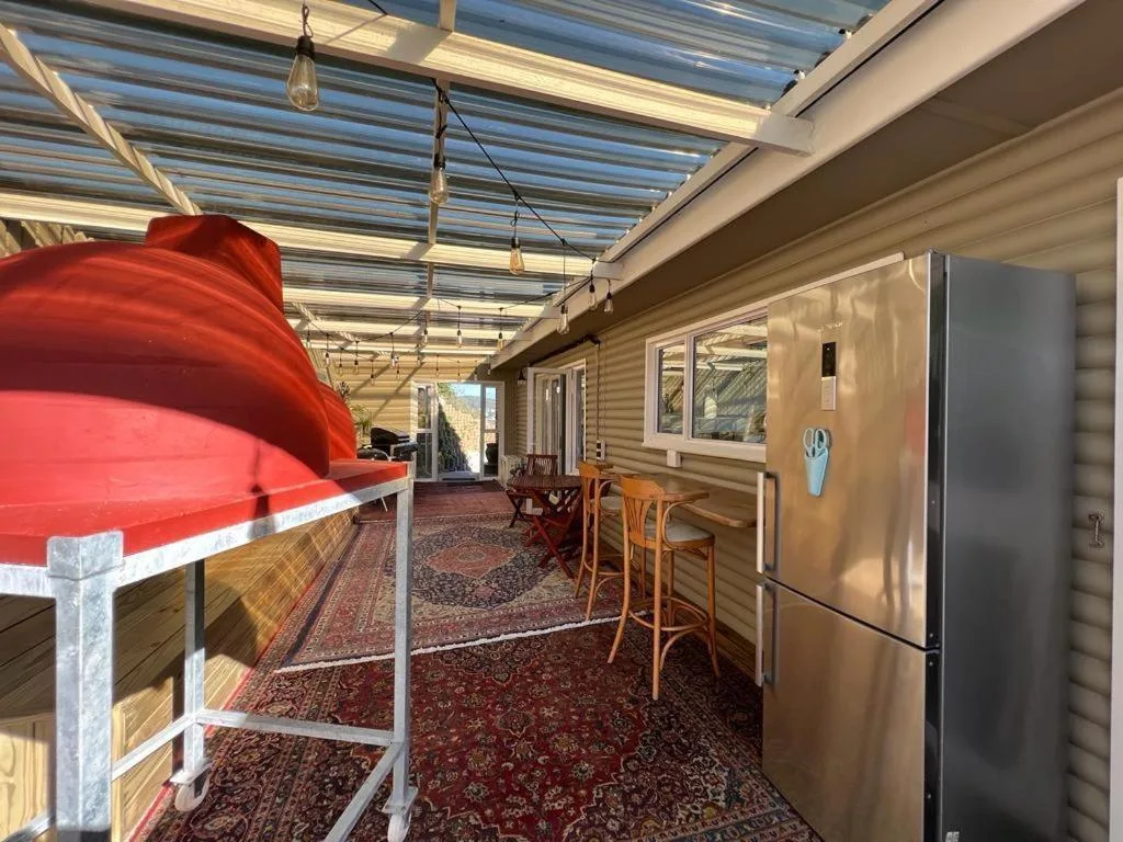 Covered outdoor deck with red lounger, bar seating, and polycarbonate roof