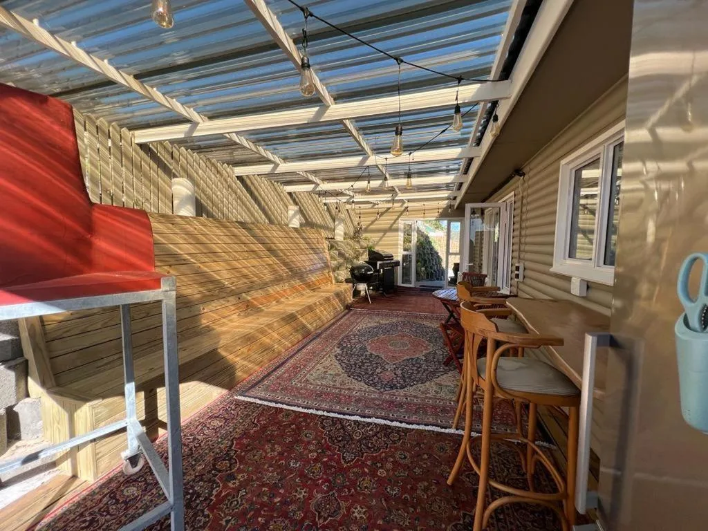 Covered patio with polycarbonate roof, wooden decking, and comfortable seating areas