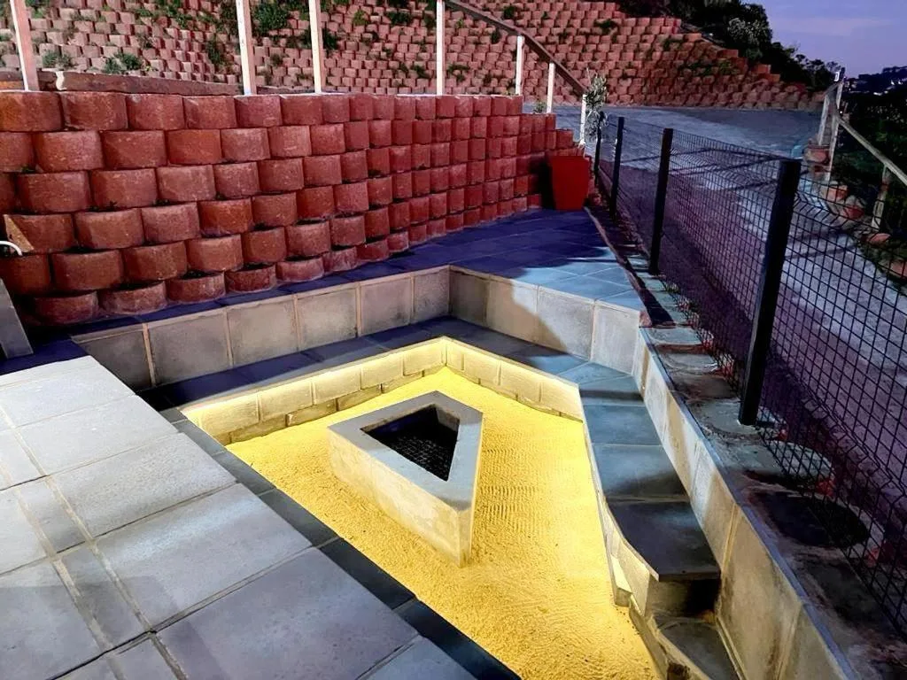 Outdoor braai area with yellow brick fireplace and concrete seating bench