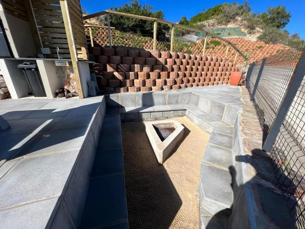 Outdoor braai area with firepit and seating on paved patio