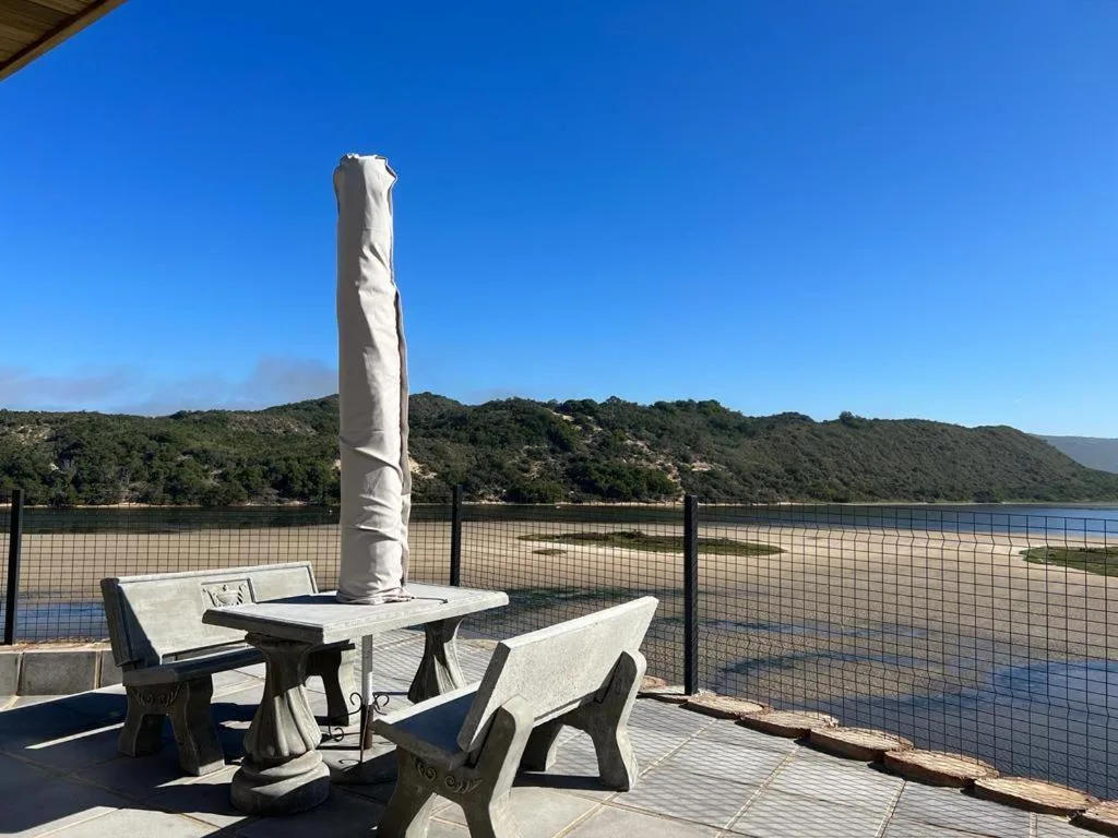 Outdoor patio with seating and umbrella overlooking lagoon and mountains