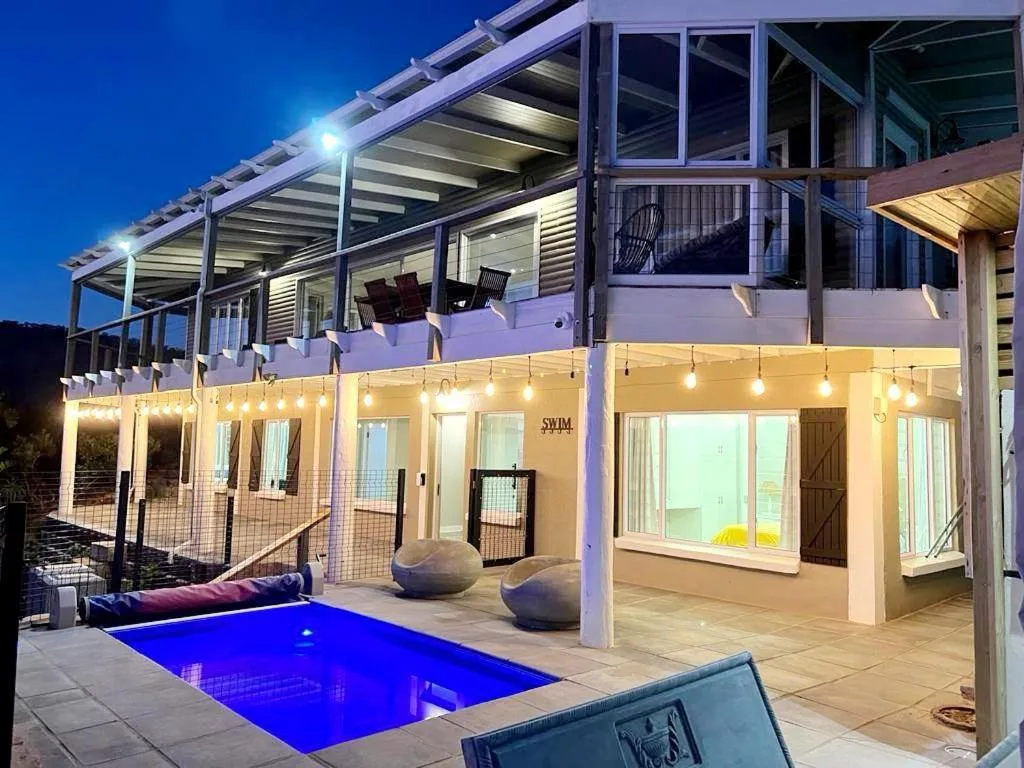 Illuminated swimming pool at dusk with modern deck and lounge seating area