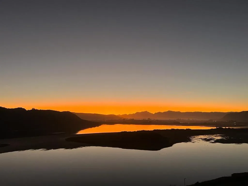Stunning sunset over Sedgefield Lagoon with mountains silhouetted against golden sky