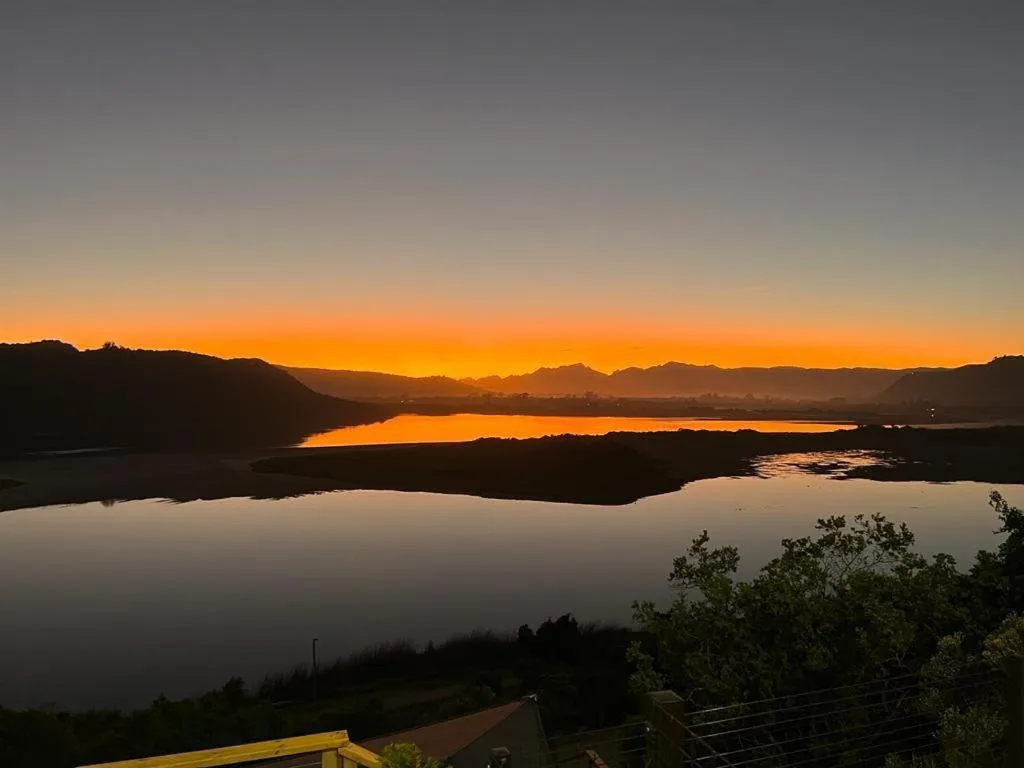 Sunset over Sedgefield Lagoon with mountains silhouetted against orange sky