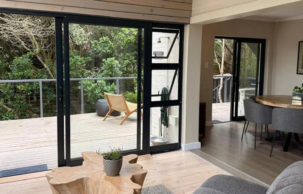 Wooden deck with lounge chair overlooking lush garden vegetation