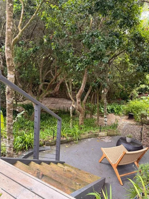 Shaded outdoor seating area with wooden chair and natural trees surrounding patio