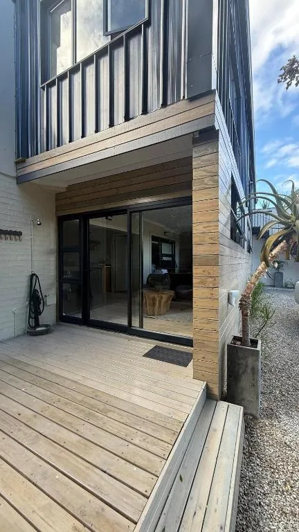Modern wooden deck with black framed sliding doors and metal railing
