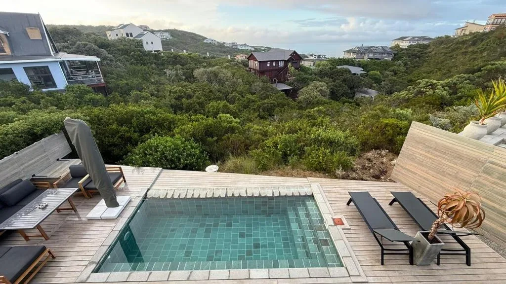 Swimming pool on wooden deck with lounge chairs and mountain views